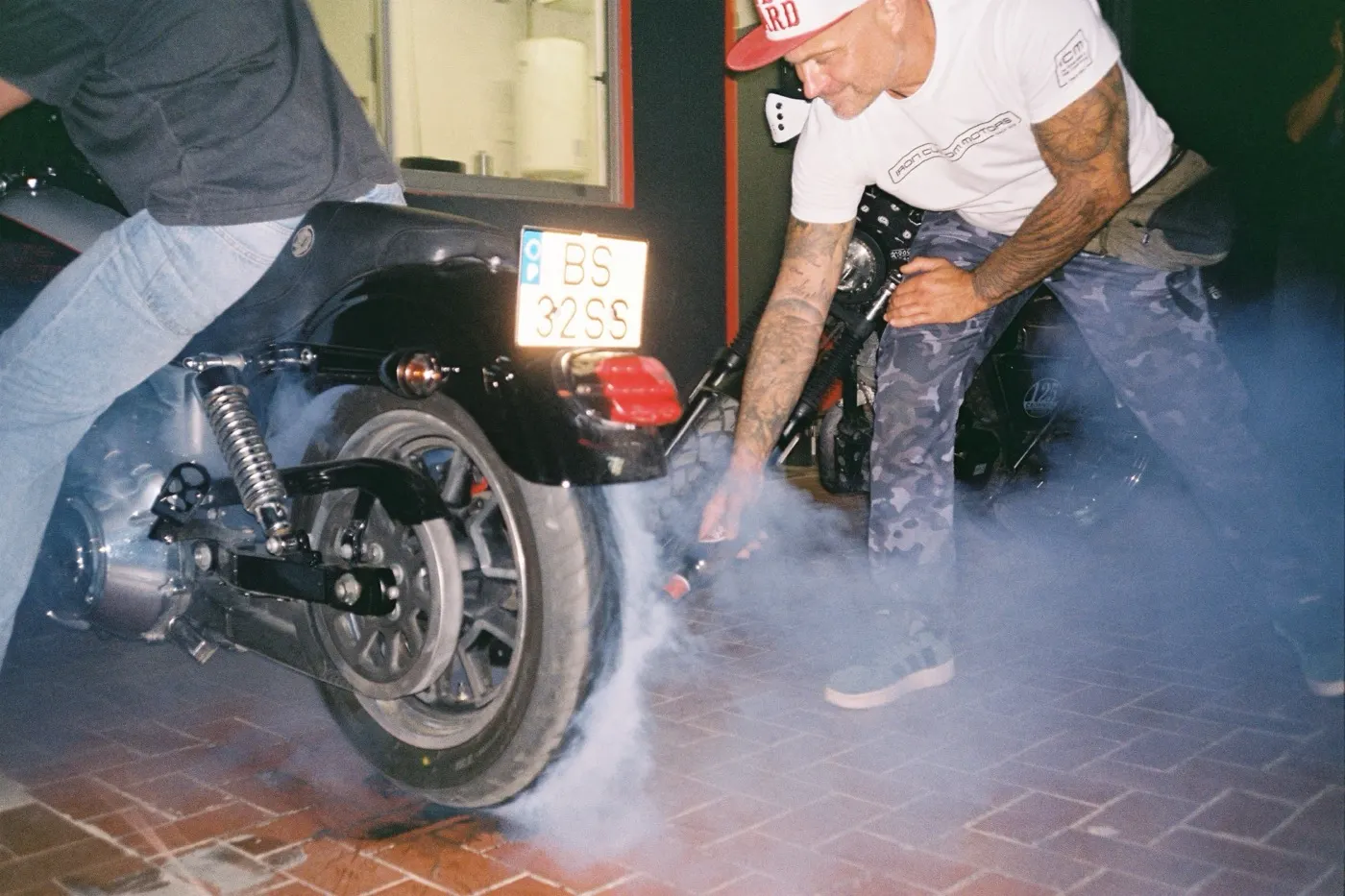 A burnout at night, a friend crouching into the tyre smoke