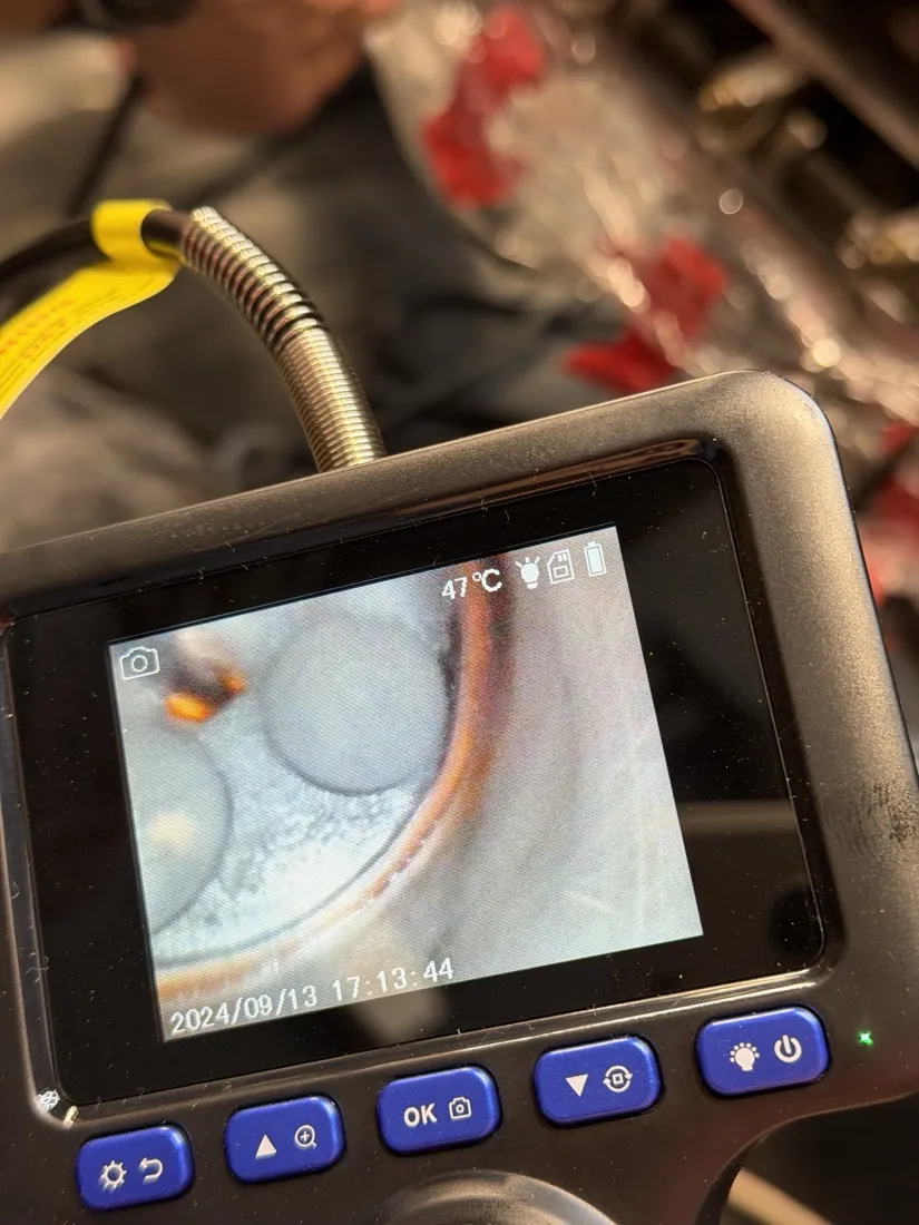 A borescope screen showing the inside of an engine cylinder, piston and valves