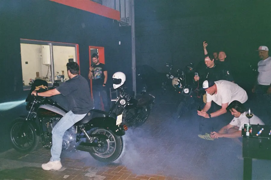 A burnout at night inside the garage, friends crouching to watch the smoke