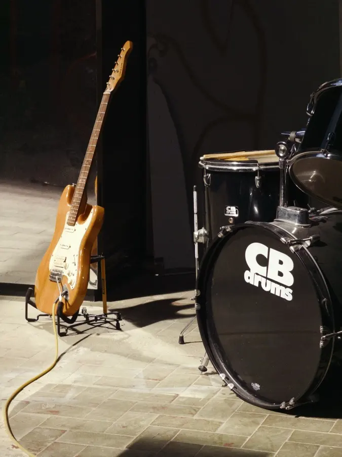 A guitar and a drum kit waiting in the afternoon sun